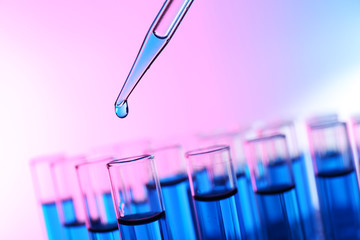 Pipette adding liquid to the one of test-tubes