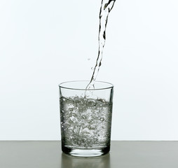 Pouring water from bottle on  glass isolated on white