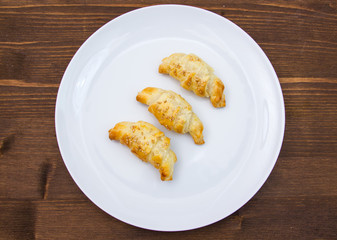 Savory croissants with sesame on wooden table seen from above