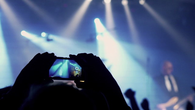 Man recording concert on cellphone and crowd having fun