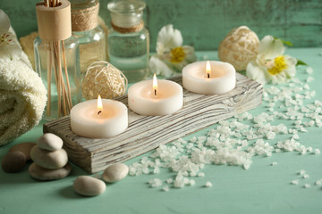 Candles, bottles sea salt and spa stones on wooden background