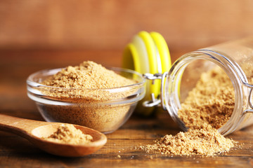 Ground mustard in glass jar and bowl on wooden background