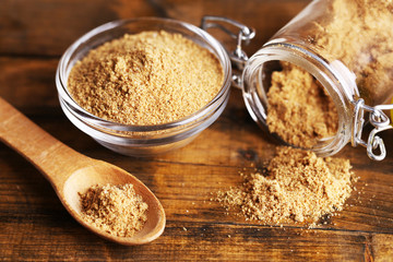 Ground mustard in glass jar and bowl on wooden background