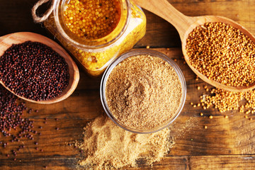 Mustard seeds, powder and sauce in glass jar, bowl and wooden