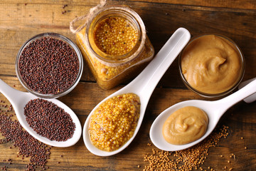 Mustard seeds, powder and sauce in spoons, bowls and glass jar