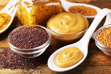 Mustard seeds, powder and sauce in glass jar, bowls and spoon