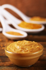 Mustard in glass bowl on wooden background
