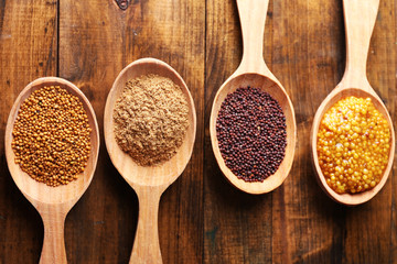 Mustard seeds, powder and sauce in wooden spoons