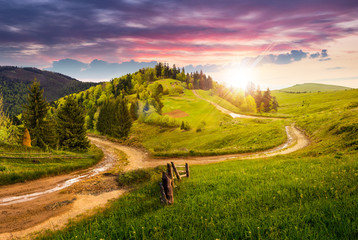 cross road on hillside meadow in mountain at sunset