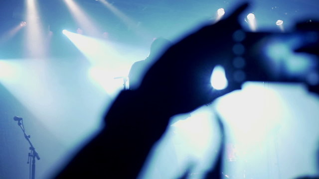 People applaud and recording rock concert in the club