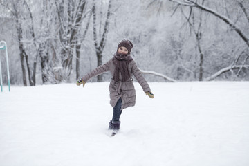 Happy little girl running on the background of snow covered wint