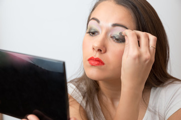 Young woman color eye shadows look in the mirror