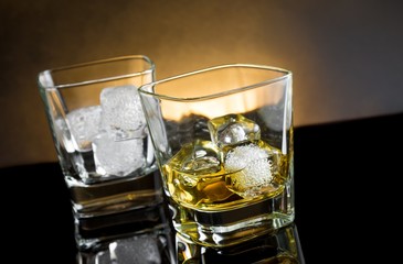 whiskey glasses with ice and warm light on black background