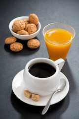 coffee, italian cookies and orange juice on black background