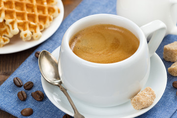 cup of coffee, waffles and a jug of milk, close-up