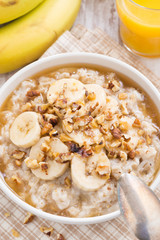 oatmeal with banana, honey and walnuts in bowl for breakfast
