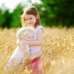 Fototapeta na wymiar Two little sisters in wheat field on summer day