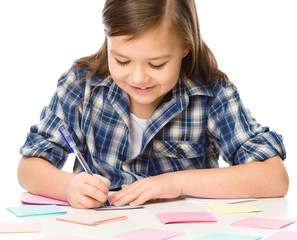 Girl is writing on color stickers using pen