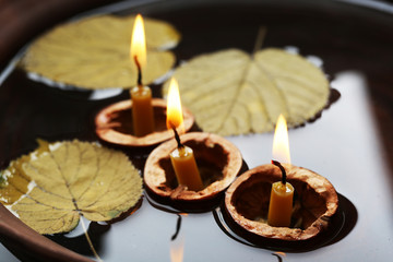 Obraz na płótnie Canvas Leaves and three nutshells with candles floating in water