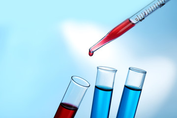 Pipette adding red fluid to the one of test-tubes
