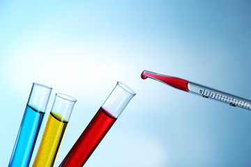 Pipette adding red fluid to the one of test-tubes