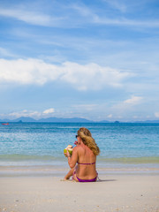Woman on the beach with coconut drink