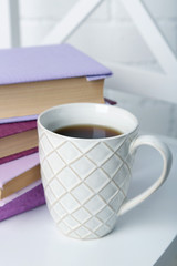 Pile of books with cup on the chair on brick wall background