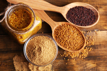 Mustard seeds, powder and sauce in glass jar, bowl and wooden