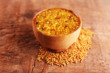 Mustard in bowl on wooden background