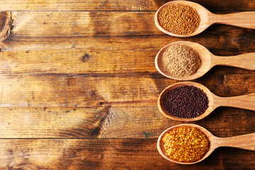 Mustard seeds, powder and sauce in wooden spoons