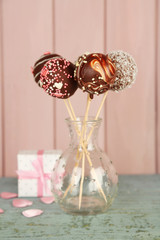 Tasty cake pops and gift on wooden background
