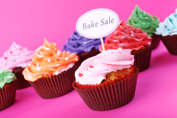Delicious cupcakes with inscription on color background