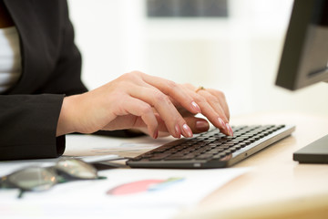 Close-up of businesswoman hands typing documents on keyboard of
