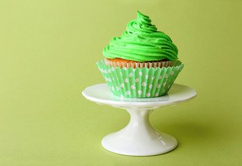 Delicious cupcake on green background