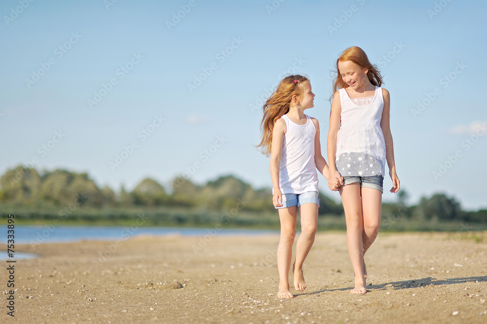 Wall mural portrait of two sisters walking on the beach