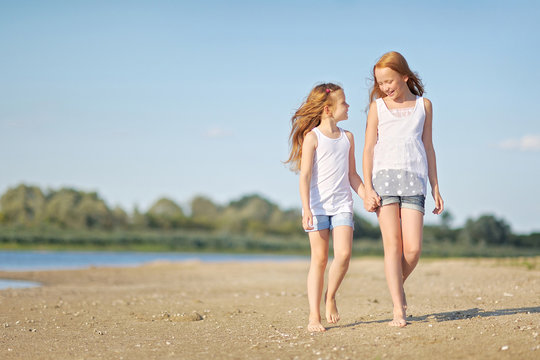portrait of two sisters walking on the beach
