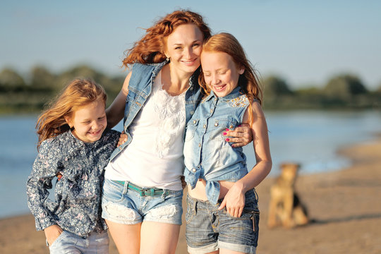 mother and her two daughters on the beach in summer
