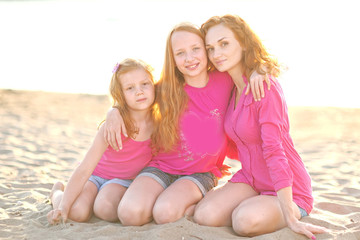 Fototapeta na wymiar mother and her two daughters on the beach in summer