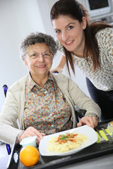 Homecarer preparing lunch for elderly woman