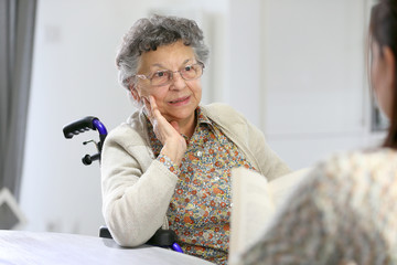 Homec arer reading book to old woman in nursing home