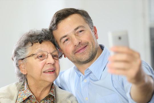 Elderly woman with son making selfy picture with smartphone
