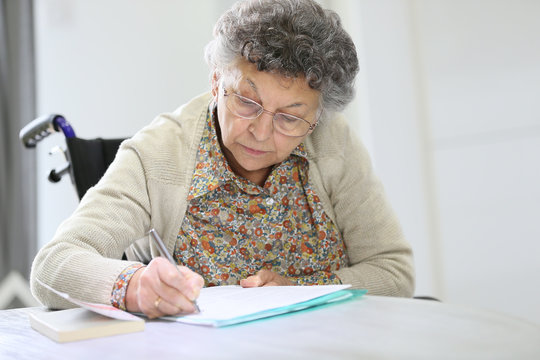 Elderly woman in wheelchair filling up medical form