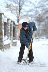 Fototapeta na wymiar Caucasian woman cleaning snow from sidewalk with shovel