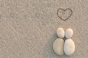 Pebbles shapes lovers with heart on the sand