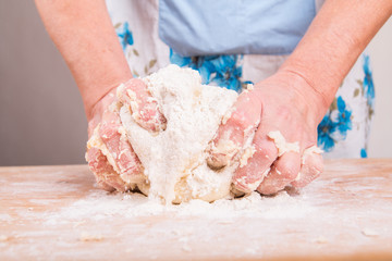 Hands kneading dough on board