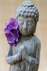 Foto auf Acrylglas grijs Boeddhabeeld met paarsebloem op bamboe achtergrond © trinetuzun