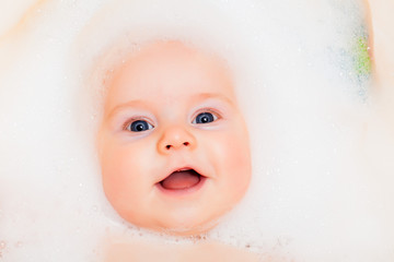 Chest baby boy bathing in a bath with foam on head