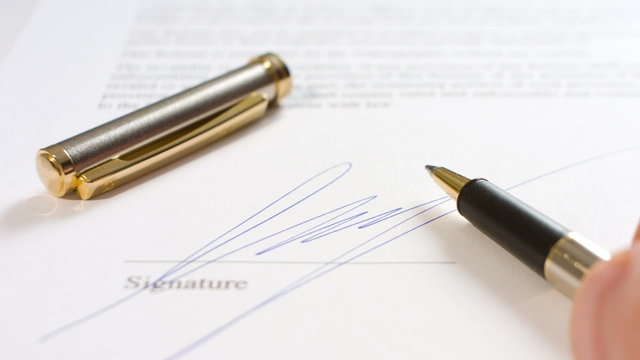 Man writing signature and pen
