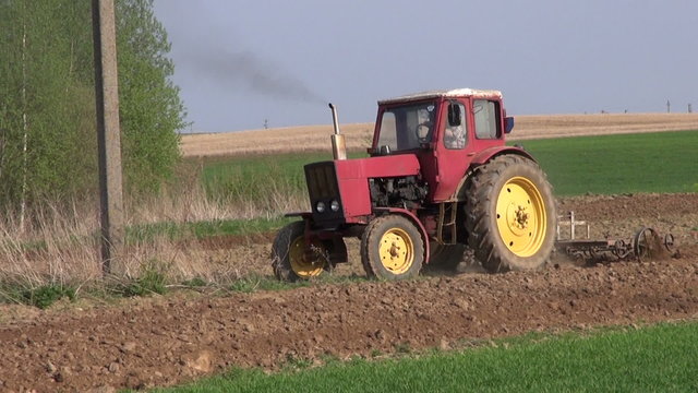 small old agriculture tractor cultivated field in spring