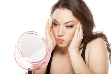 young woman in front of the mirror tightens her face